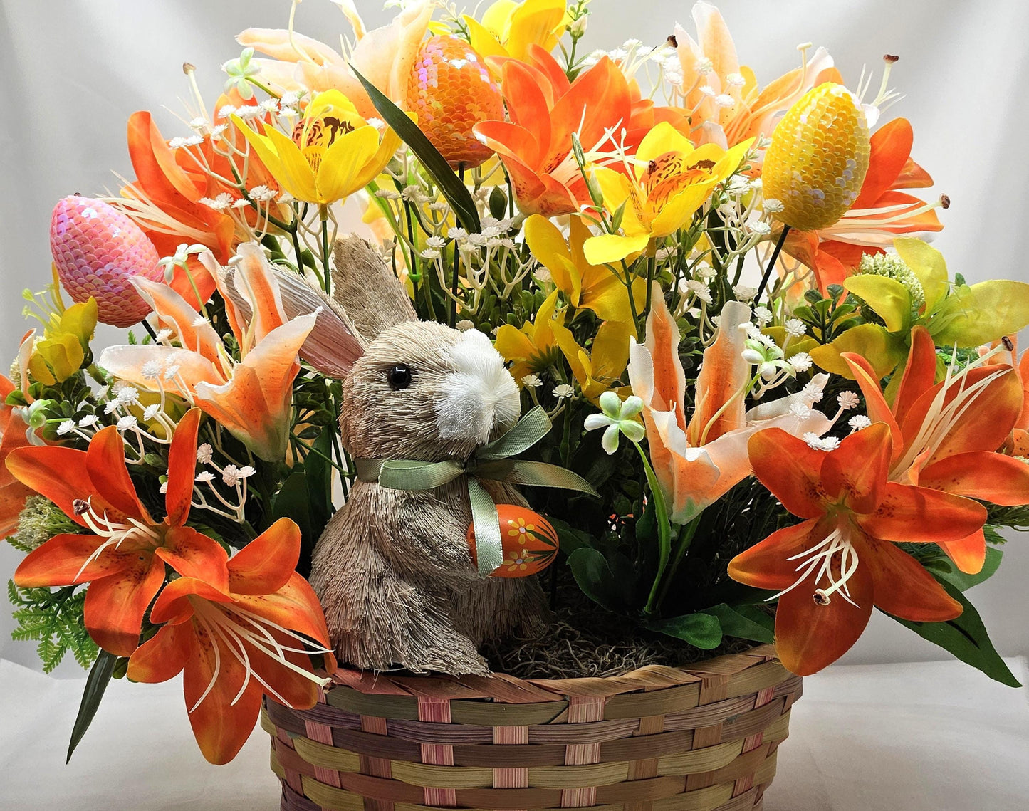 Rattan Easter Bunny in a Multi-colored Basket, Surrounded by Lush and Lovely Lilies, Greens, Baby's Breath,Orange and Yellow Hues
