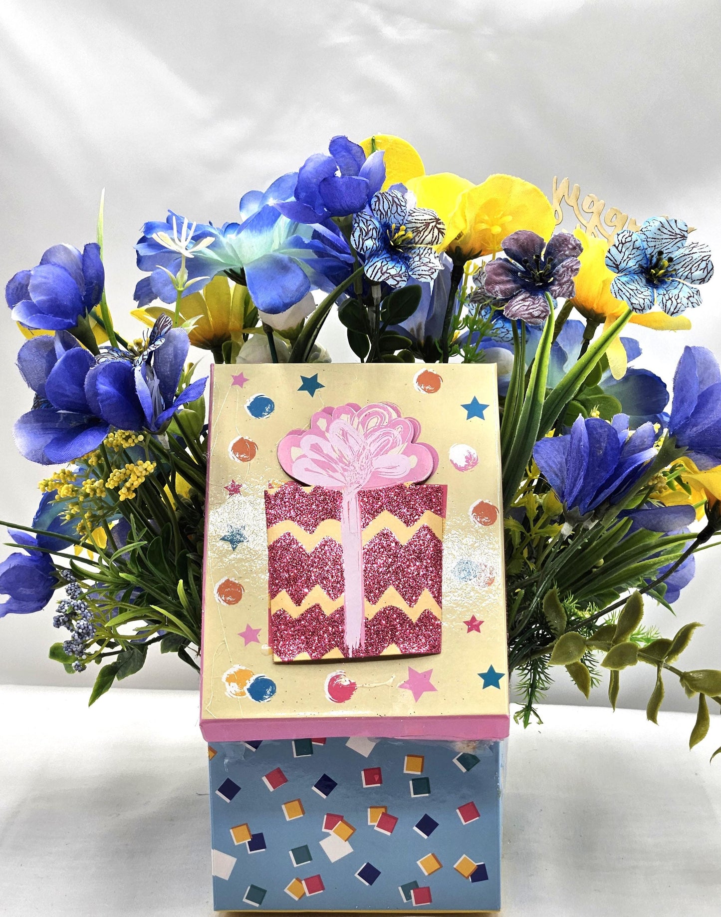 Birthday Flower Arrangement set in Blue Gift Box, Glittery BD Cake on the Lid, Lovely Blue/Yellow Blooms, Cute Bunnies, Baloons, Gifts
