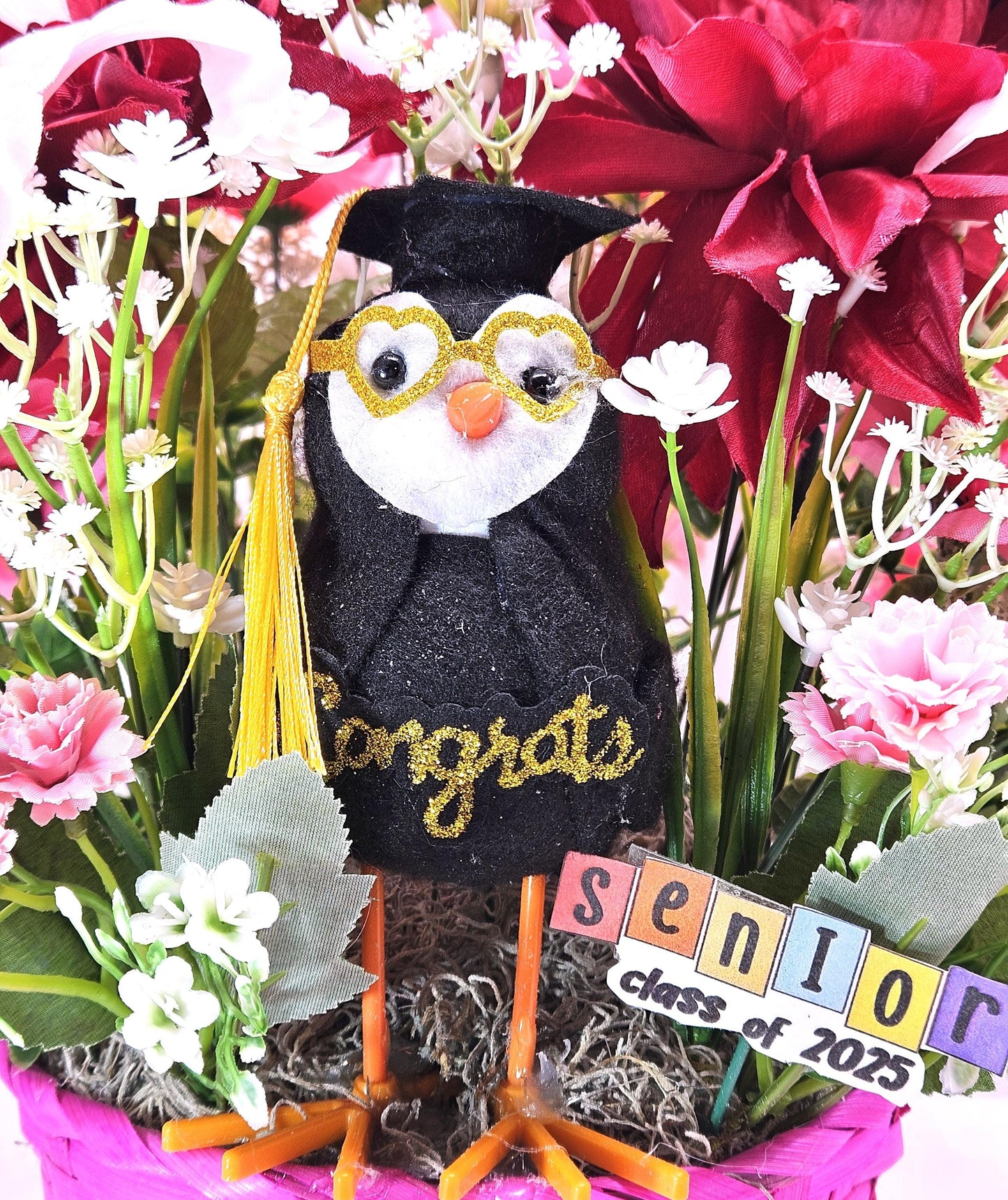 Celebrate The Graduate W/Pink Wicker Basket of Flowers/Greenery/A Sparkly Graduation Hat/A Graduate Bird In Front/Congratulations Messa