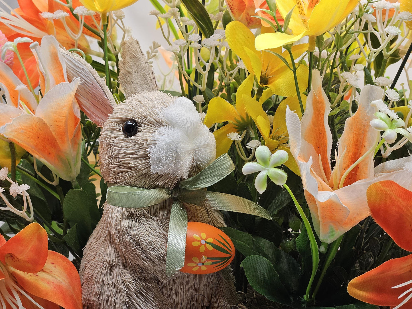 Rattan Easter Bunny in a Multi-colored Basket, Surrounded by Lush and Lovely Lilies, Greens, Baby's Breath,Orange and Yellow Hues