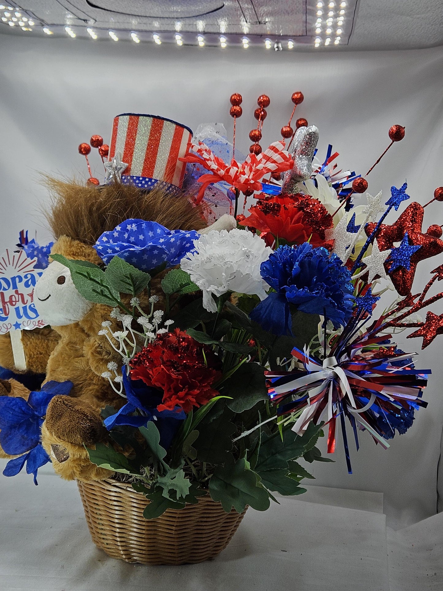 Stuffed Patriotic Steer Celebrating the USA within a Garden of Red/White/Blue Roses/Carnations/Greenery/Sparkly Stars/Other Glitter Accents