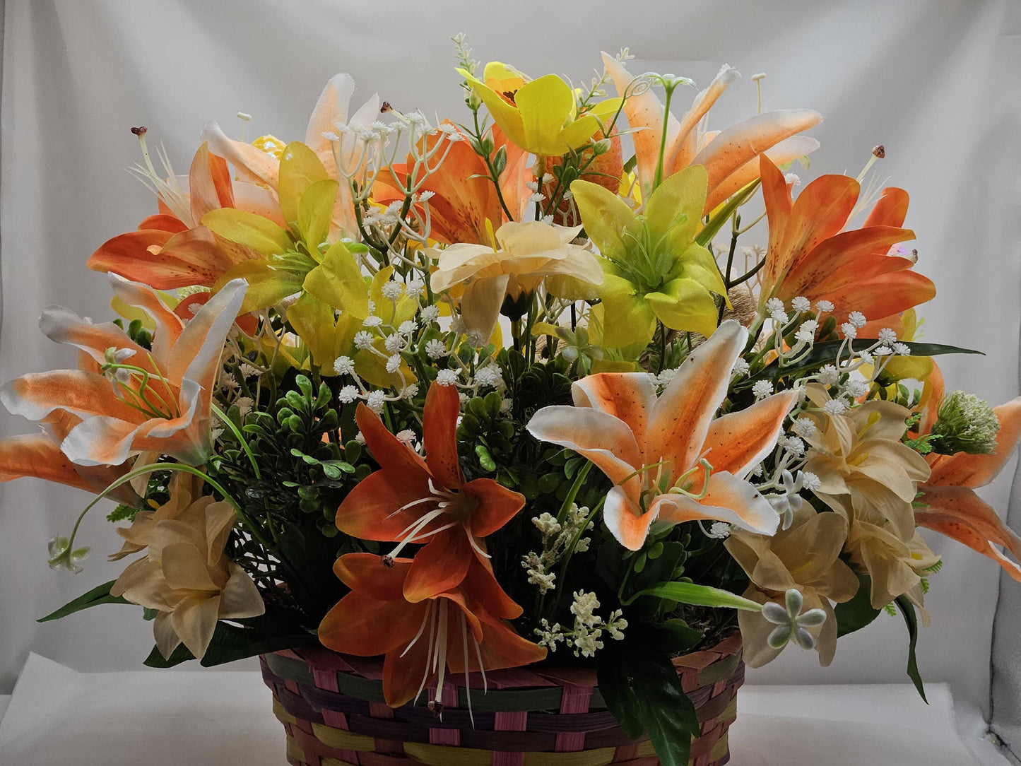 Rattan Easter Bunny in a Multi-colored Basket, Surrounded by Lush and Lovely Lilies, Greens, Baby's Breath,Orange and Yellow Hues