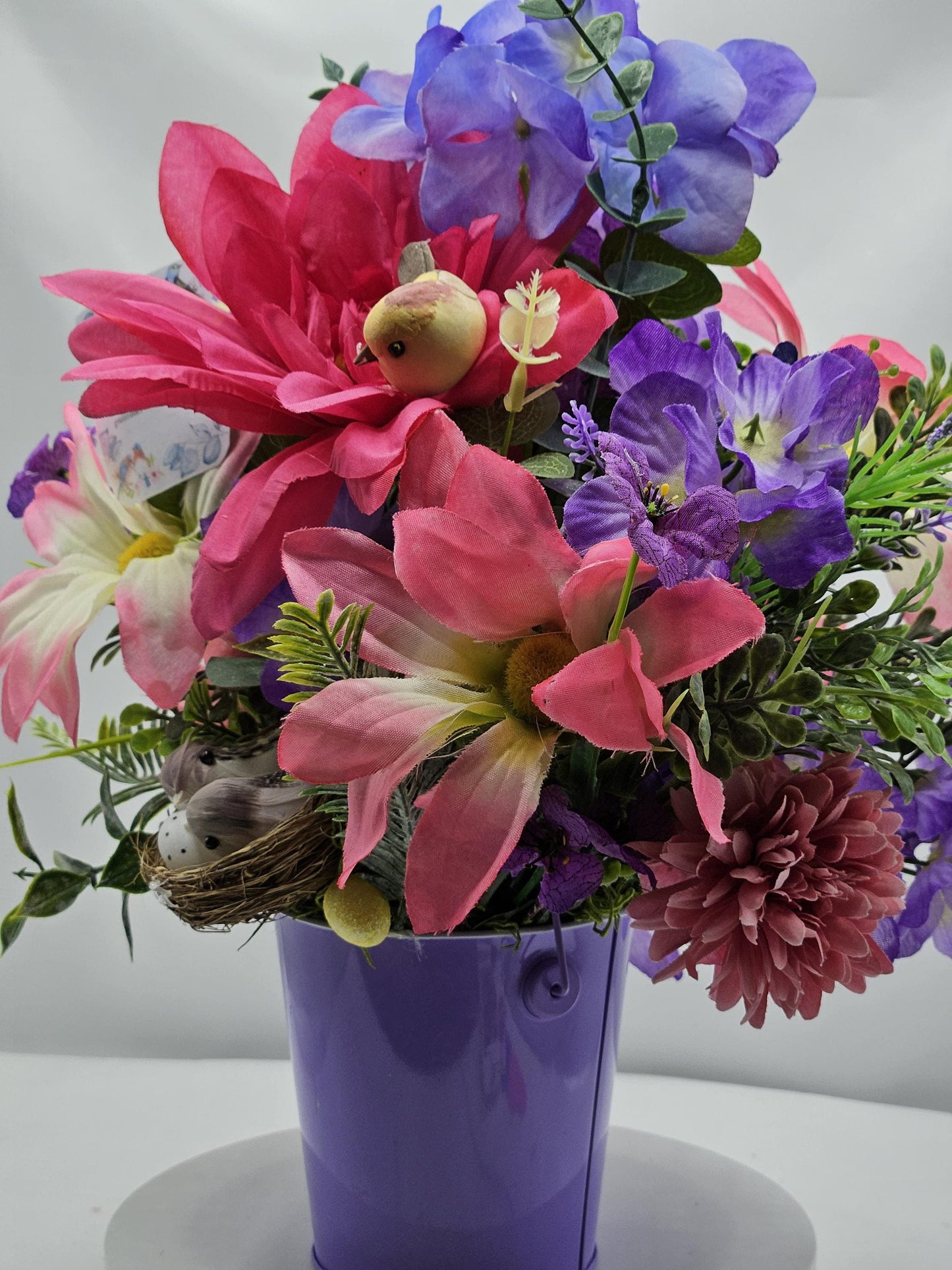 Charming Thinking Of You Bouquet set in a light purple container and accented with birds in a nest and/Atop Flowers/Pink/White/Blue/Greenery