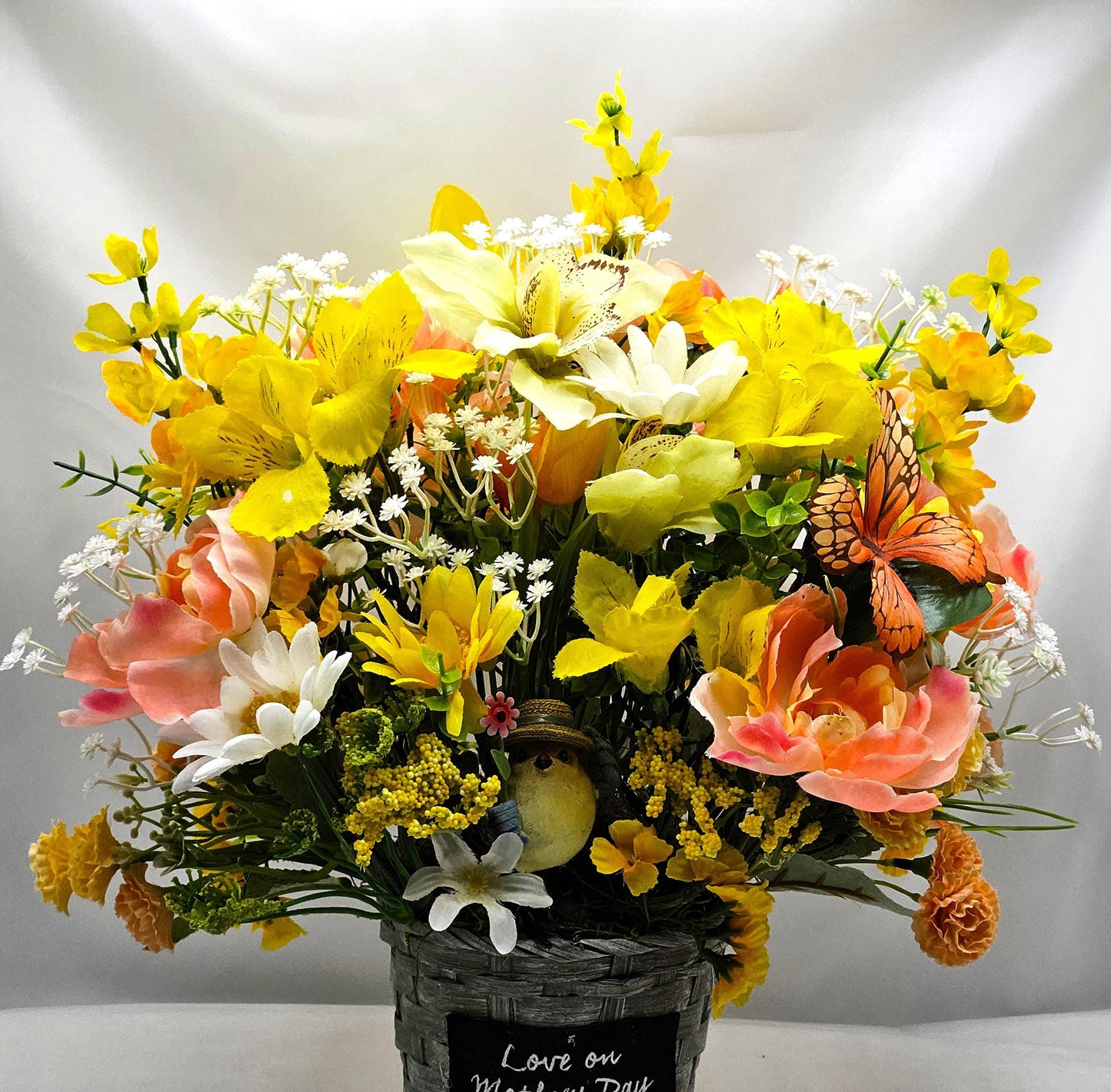 Mother's Day Bouquet in Wicker Type Pot/Love on Mother's Day/Featuring a Cheerful Bird in a Garden of Vibrant Yellow/Peach Flowers/Butterfly