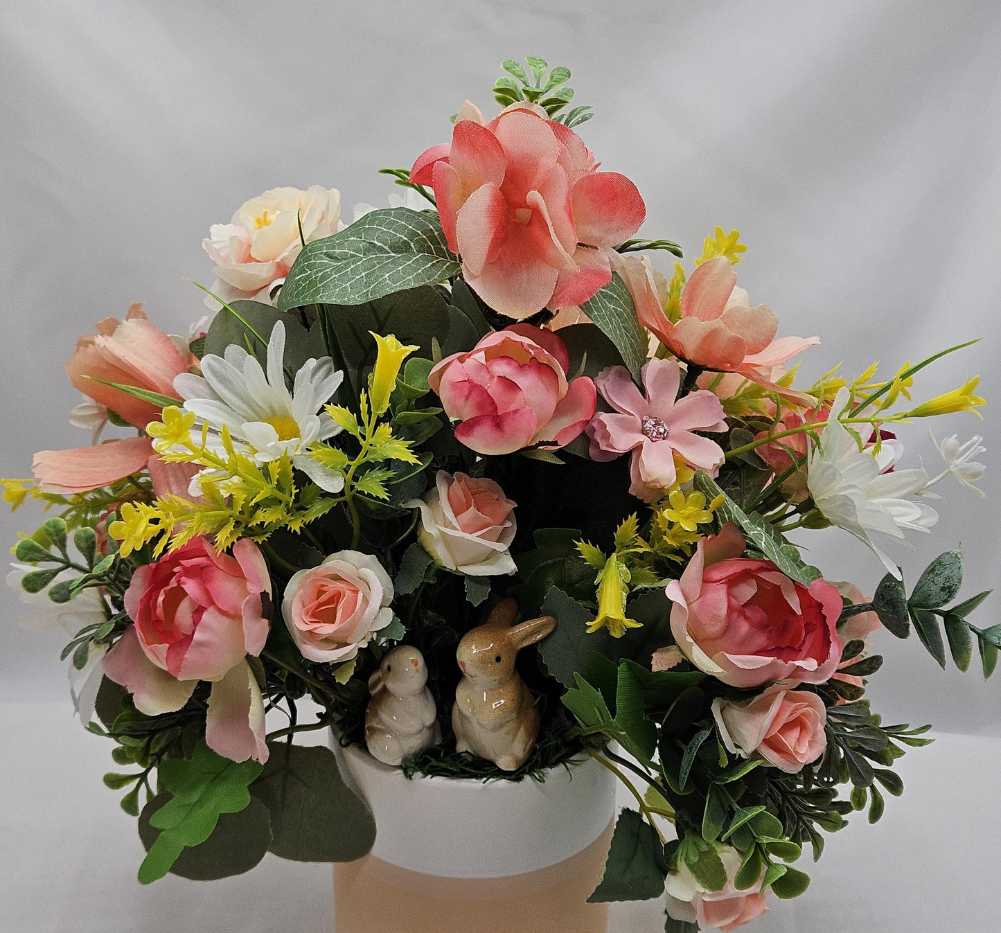 Ceramic Bunnies in a Pink/Peach/Yellow Flower Garden, Lush Greens and Baby's Breath, All Nestled in a Two Tone Ceramic Beige/White Vase