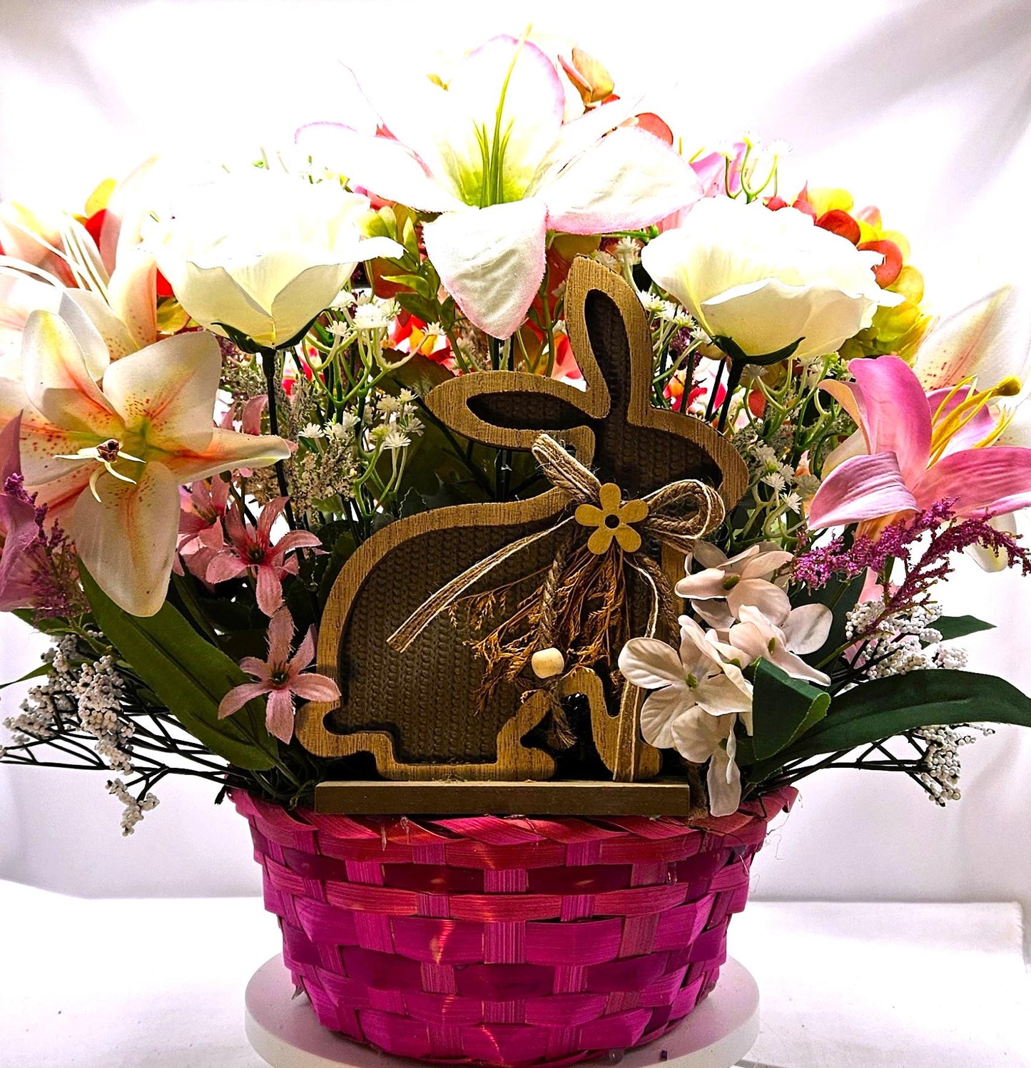 Bright Blue or Pink Easter Basket With Wooden Rabbit Accents in front of Vibrant Pin/White or Purple/White Lily Garden
