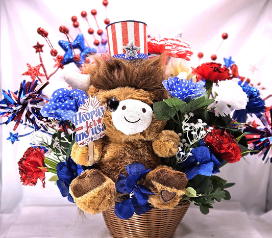 Stuffed Patriotic Steer Celebrating the USA within a Garden of Red/White/Blue Roses/Carnations/Greenery/Sparkly Stars/Other Glitter Accents