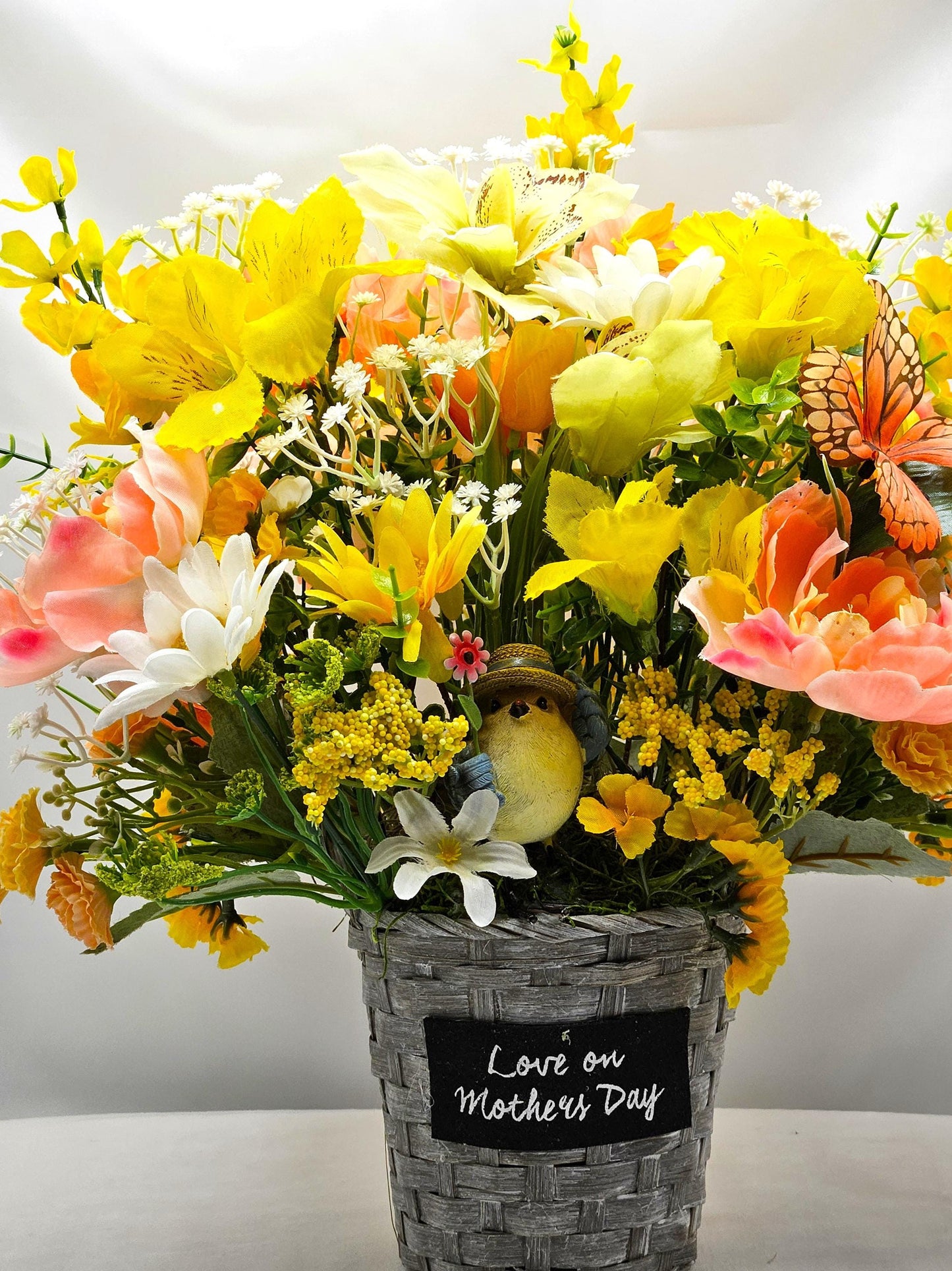 Mother's Day Bouquet in Wicker Type Pot/Love on Mother's Day/Featuring a Cheerful Bird in a Garden of Vibrant Yellow/Peach Flowers/Butterfly