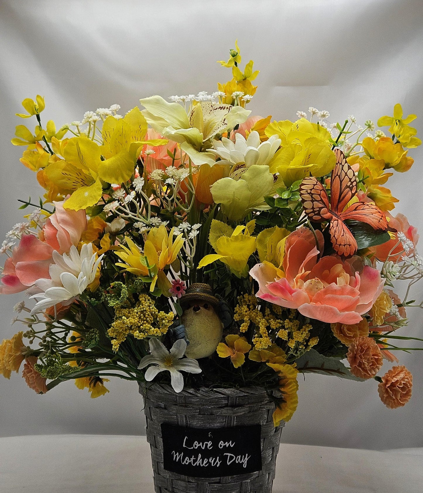 Mother's Day Bouquet in Wicker Type Pot/Love on Mother's Day/Featuring a Cheerful Bird in a Garden of Vibrant Yellow/Peach Flowers/Butterfly