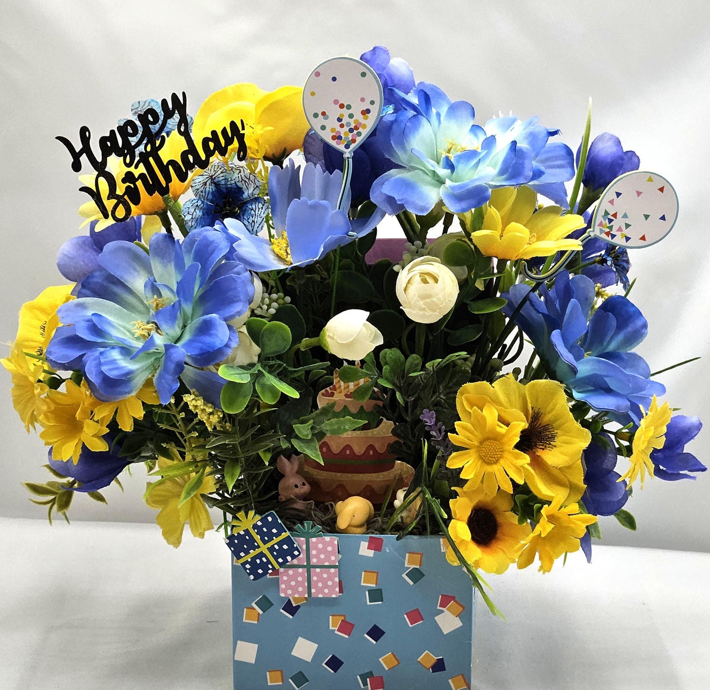 Birthday Flower Arrangement set in Blue Gift Box, Glittery BD Cake on the Lid, Lovely Blue/Yellow Blooms, Cute Bunnies, Baloons, Gifts
