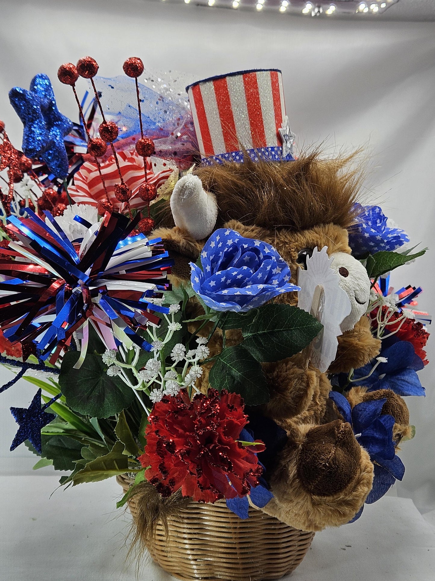 Stuffed Patriotic Steer Celebrating the USA within a Garden of Red/White/Blue Roses/Carnations/Greenery/Sparkly Stars/Other Glitter Accents