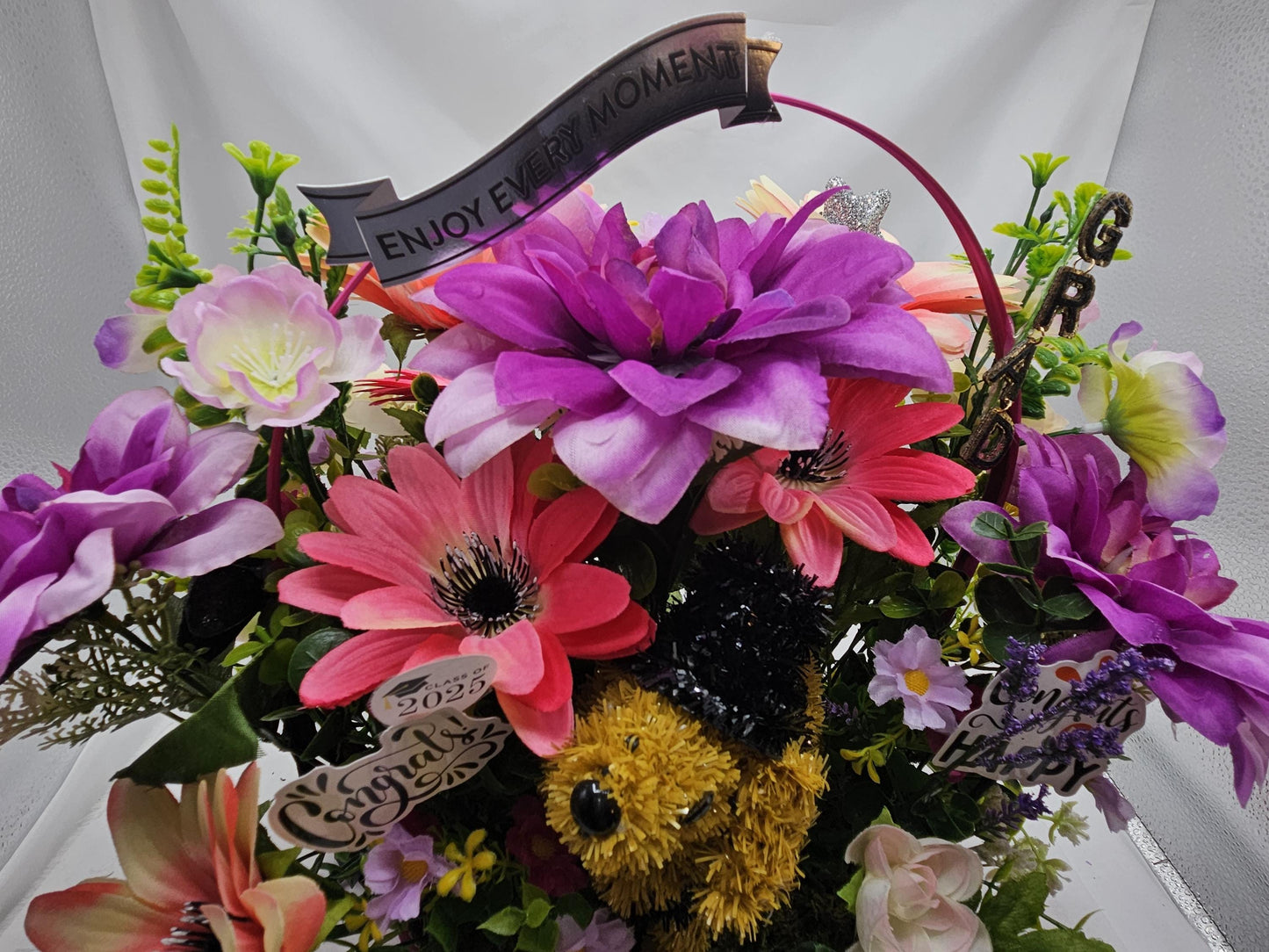 Whimsical Graduation Flower Arrangement in Pink Wicker Basket, Congrats and Enjoy Every Moment Signs with Pink/Purple Florals/Greenery
