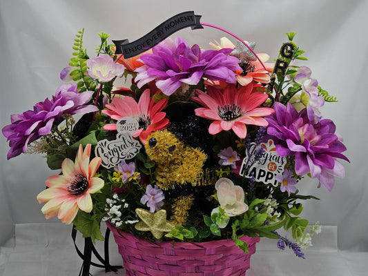 Whimsical Graduation Flower Arrangement in Pink Wicker Basket, Congrats and Enjoy Every Moment Signs with Pink/Purple Florals/Greenery